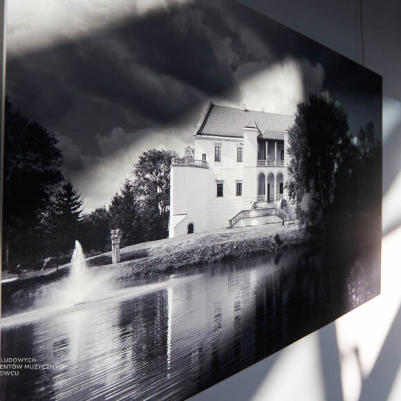 zdjęcie zamku w szydłowcu w kolorach bieli i czerni zawiedzone na ścianie na które padają światła i cienie rzucane przez okno którego nie widać na grafice.