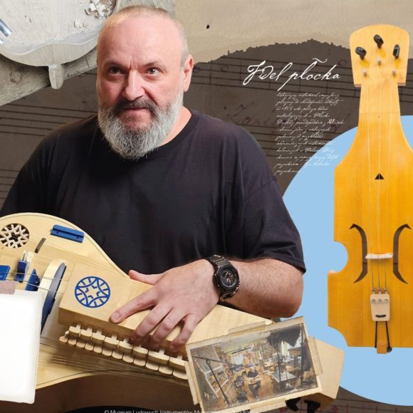kościółek Zdjęcie. Mężczyzna z brodą trzyma w rękach drewniany instrument z elementami niebieskiego - lirę korbową. Obok fidel płocka na niebieskim kole i fragment rękopisu.