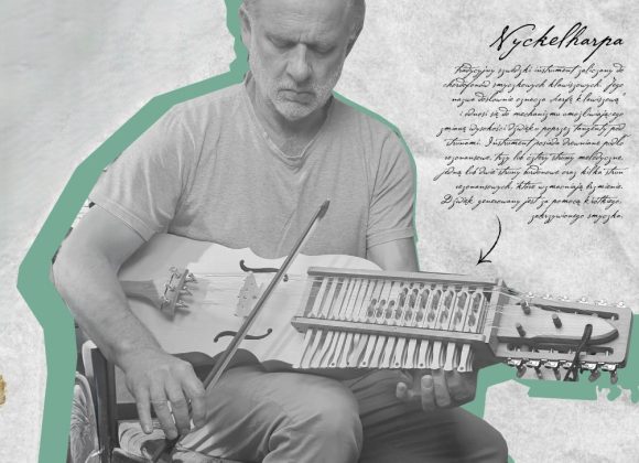 Zdjęcie. Czarno-białe. Mężczyzna o długich włosach siedzi.