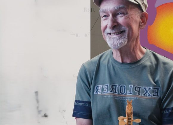 Zdjęcie. Mężczyzna w zielonkawej koszulce z krótkim rękawem, na głowie czapka z daszkiem.