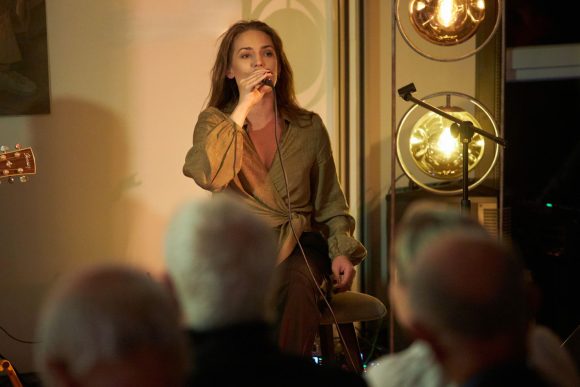 Wokalistka z zespołu Czarnina oraz publiczność podczas koncertu w Muzeum Ludowy Instrumentów Muzycznych