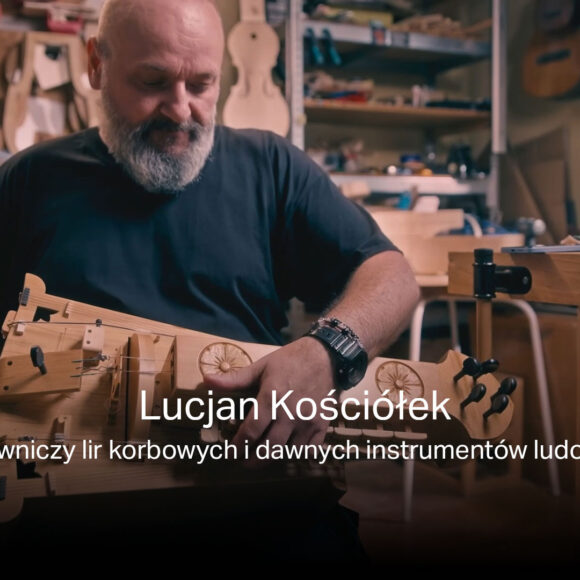 Na zdjęciu Lucjan Kościółek w swojej pracowni gra na lirze korbowej, którą sam zbudował. Za nim warsztat z narzędziami.