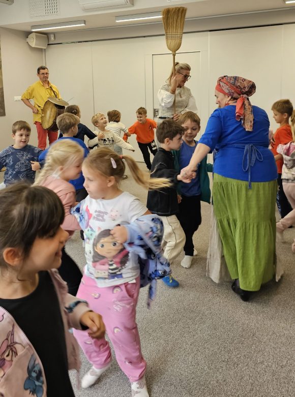 Aktorzy z teatrzyku „Słuchaj uchem” oraz dziecięca publiczność podczas spektaklu „Kusy Janek”. Dzieci uczestniczą w zabawie tanecznej.