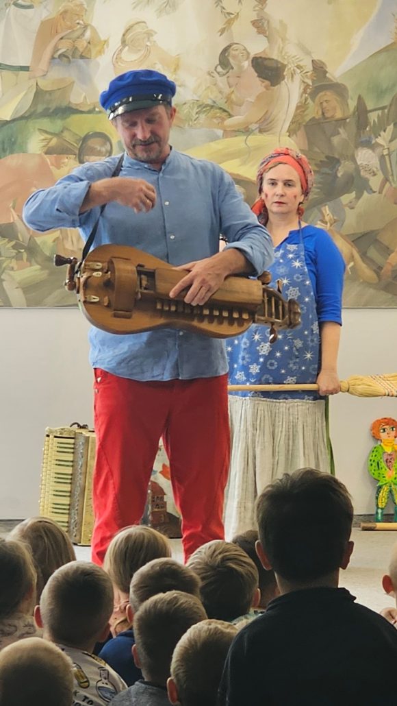 Aktorzy z teatrzyku „Słuchaj uchem” prezentujący instrumenty lirę korbową podczas spektaklu „Kusy Janek”.