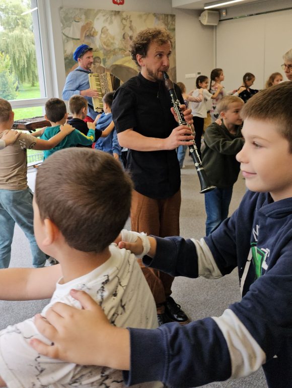 Aktorzy: klarnecista i akordeonista z teatrzyku „Słuchaj uchem” oraz bawiące się dzieci podczas spektaklu „Kusy Janek”.