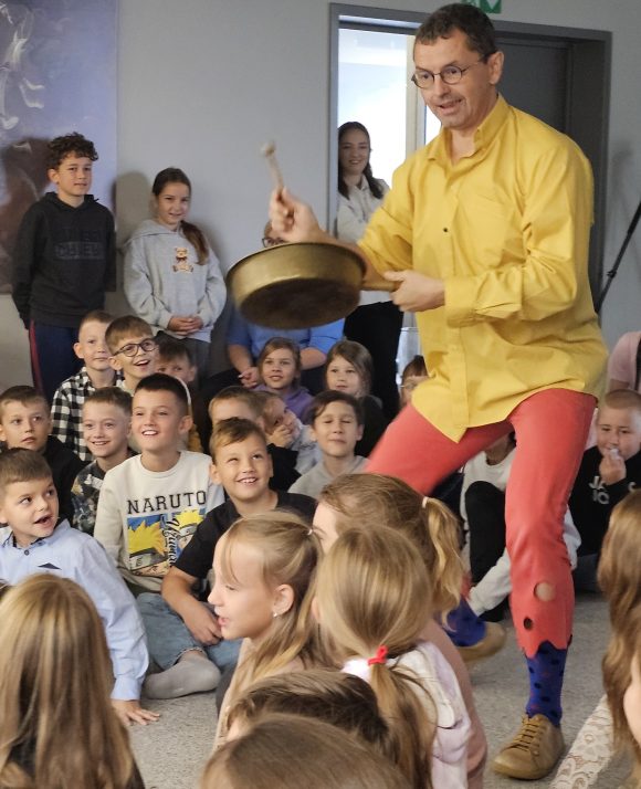 Aktor grający na patelni z teatrzyku „Słuchaj uchem” oraz dziecięca publiczność podczas spektaklu „Kusy Janek”.