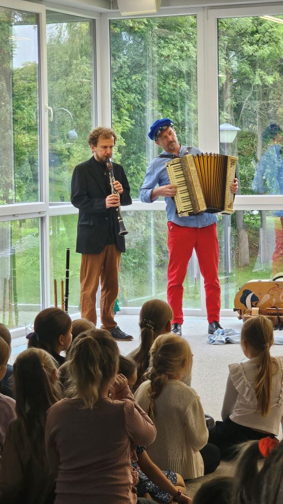 Aktorzy: klarnecista i akordeonista z teatrzyku „Słuchaj uchem” oraz dziecięca publiczność podczas spektaklu „Kusy Janek”.