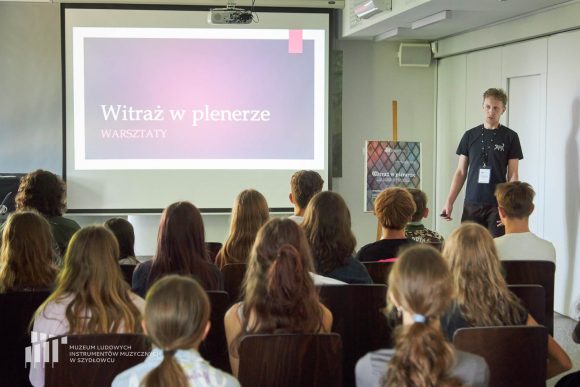 Prezentacja historii witrażu przez prowadzącego prelekcję oraz uczniowie Publicznej Szkoły Podstawowej nr 2 im. Jana Pawła II w Szydłowcu podczas zajęć artystycznych „Witraż w plenerze”.