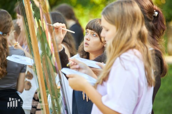Na pierwszym planie uczniowie Publicznej Szkoły Podstawowej nr 2 im. Jana Pawła II w Szydłowcu podczas zajęć artystycznych „Witraż w plenerze”.