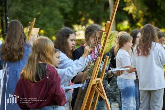 Na pierwszym planie uczniowie Publicznej Szkoły Podstawowej nr 2 im. Jana Pawła II w Szydłowcu podczas zajęć artystycznych „Witraż w plenerze”.