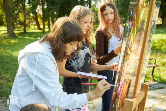 Na pierwszym planie uczniowie Publicznej Szkoły Podstawowej nr 2 im. Jana Pawła II w Szydłowcu podczas zajęć artystycznych „Witraż w plenerze”.