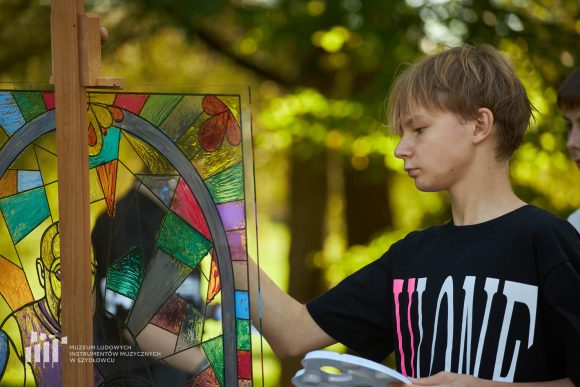 Na pierwszym planie uczeń Publicznej Szkoły Podstawowej nr 2 im. Jana Pawła II w Szydłowcu podczas zajęć artystycznych „Witraż w plenerze”.