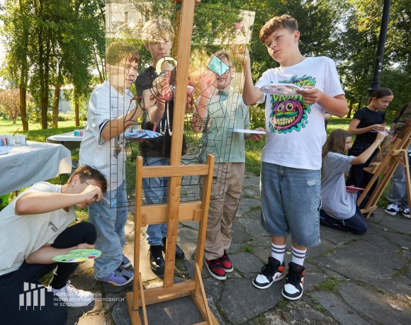 Na pierwszym planie uczniowie Publicznej Szkoły Podstawowej nr 2 im. Jana Pawła II w Szydłowcu podczas zajęć artystycznych „Witraż w plenerze”. W tle park.