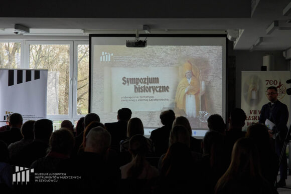 Jasna prezentacja na temat sympozjum historycznego, na pierwszym planie cienie publiczności.